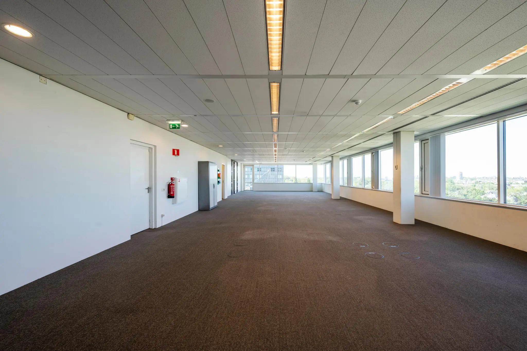 Leeg kantoorruimte met tapijtvloer en grote ramen aan de Thomas R. Malthusstraat.